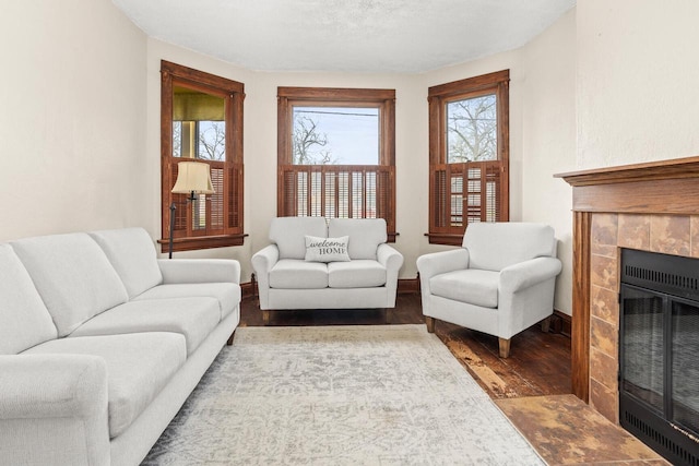 living area featuring baseboards, a tiled fireplace, and wood finished floors