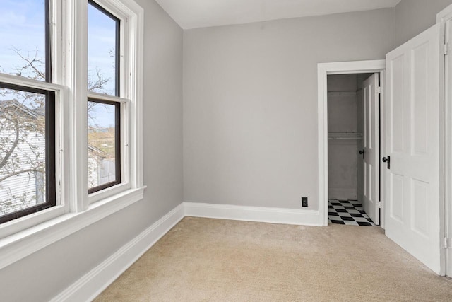unfurnished bedroom featuring baseboards, multiple windows, light carpet, and a closet
