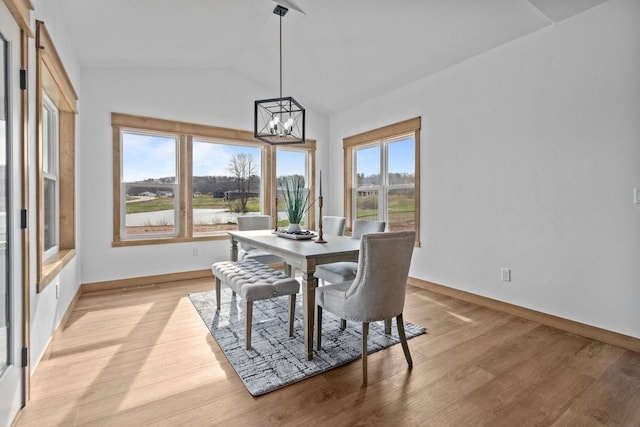 dining space featuring an inviting chandelier, baseboards, light wood-style floors, and lofted ceiling