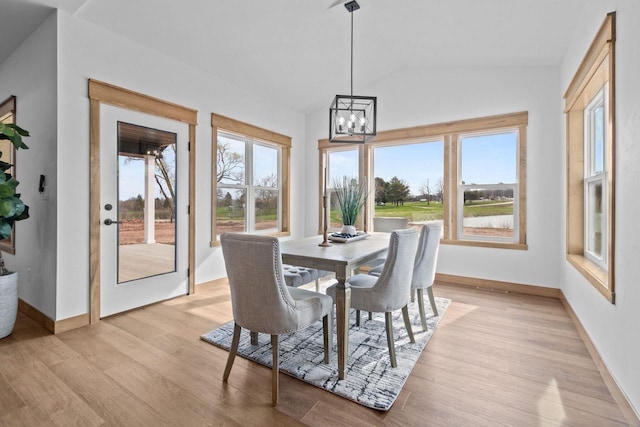 dining area featuring an inviting chandelier, light wood finished floors, baseboards, and vaulted ceiling