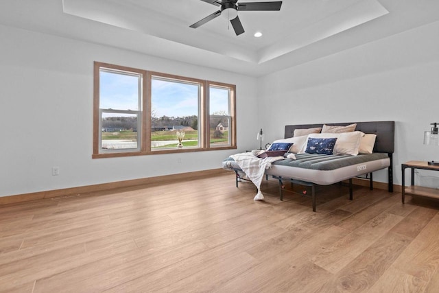 bedroom with a ceiling fan, light wood-type flooring, a raised ceiling, baseboards, and recessed lighting