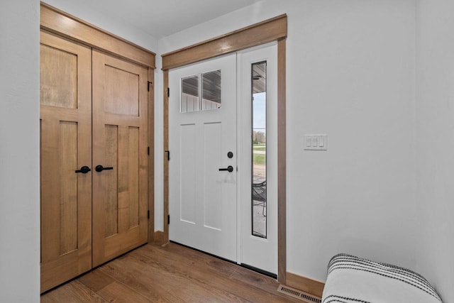 entryway with baseboards, wood finished floors, and visible vents