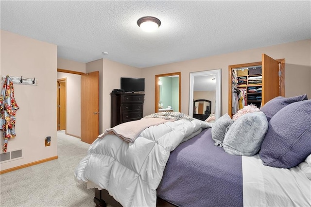 carpeted bedroom featuring a textured ceiling, visible vents, and baseboards