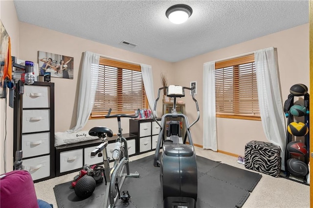 workout area featuring visible vents, a textured ceiling, and baseboards