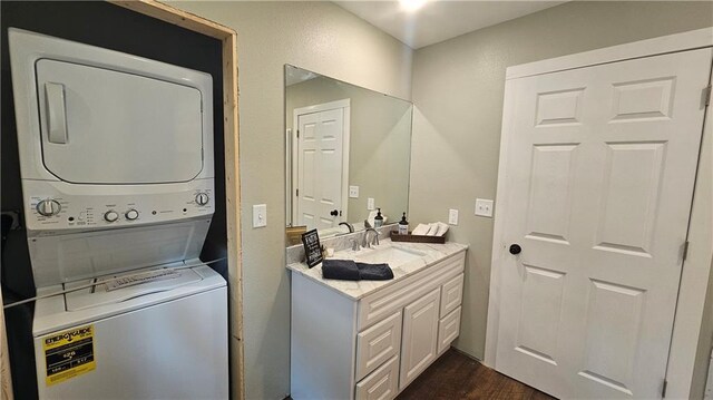 10039 State Highway 27, Hayward, WI 54843 - clothes washing area featuring a sink, stacked washer and clothes dryer, dark wood-type flooring, and laundry area