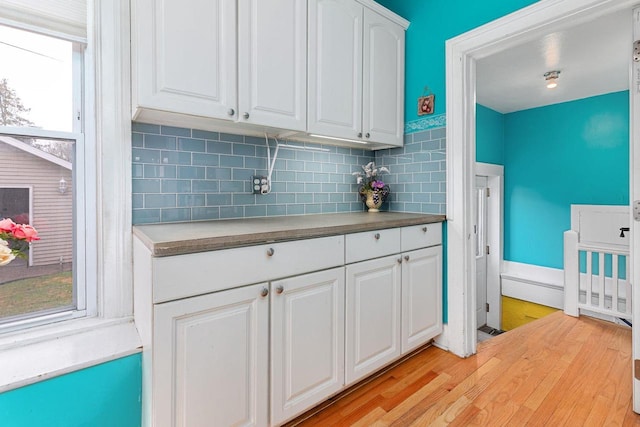 1221 S Madison St, Appleton, WI 54915 - kitchen with light countertops, white cabinetry, baseboards, light wood-type flooring, and backsplash