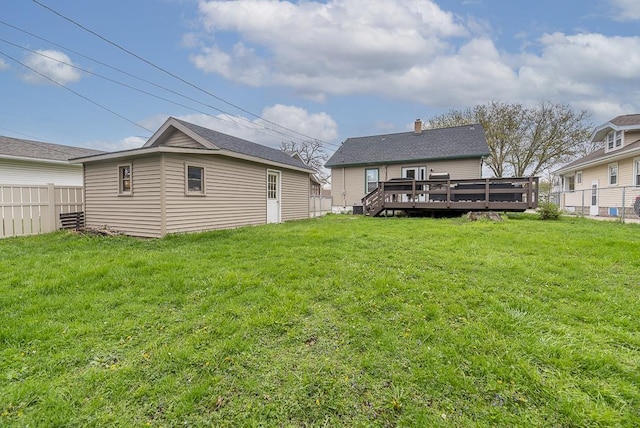 rear view of house featuring fence, a yard, and a deck