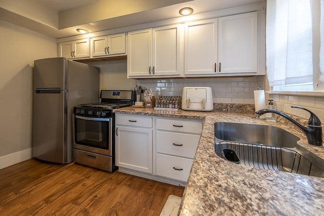 kitchen with a sink, appliances with stainless steel finishes, dark wood-style floors, and tasteful backsplash
