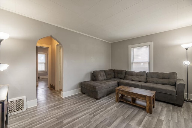 living room with visible vents, arched walkways, wood finished floors, and a healthy amount of sunlight
