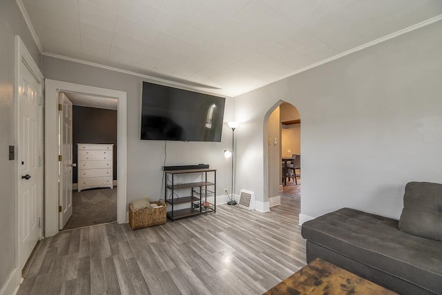 living room featuring crown molding, arched walkways, baseboards, wood finished floors, and visible vents