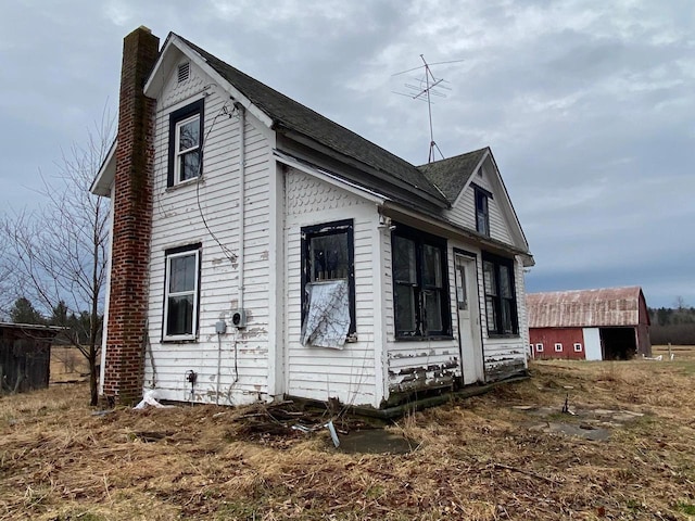 186 Abrahams Rd, Skandia, MI 49885 - view of home's exterior featuring a shingled roof and a chimney