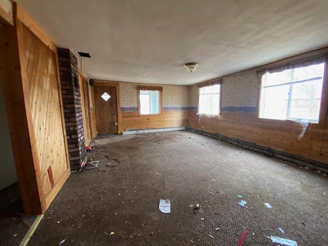 186 Abrahams Rd, Skandia, MI 49885 - unfurnished living room featuring wood walls