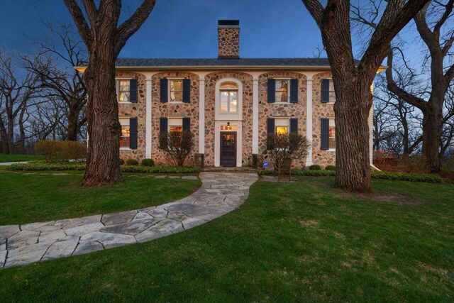 view of front of property with a chimney, stone siding, and a front lawn