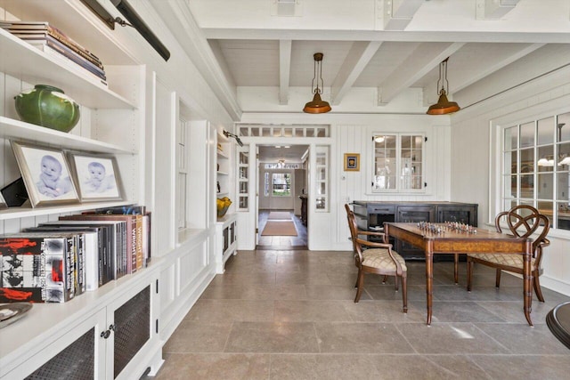 dining area with beamed ceiling and a decorative wall