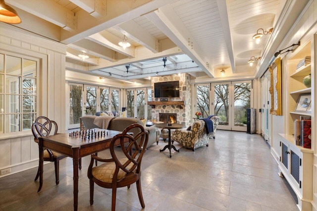 dining room with beamed ceiling, baseboards, a fireplace, and french doors