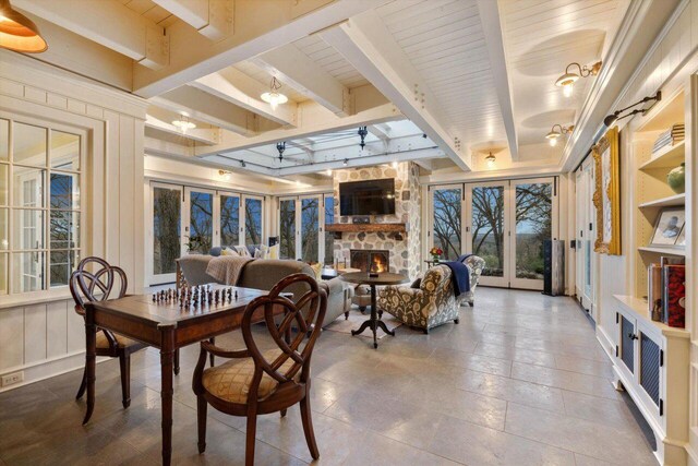 dining room with french doors, a fireplace, and beamed ceiling