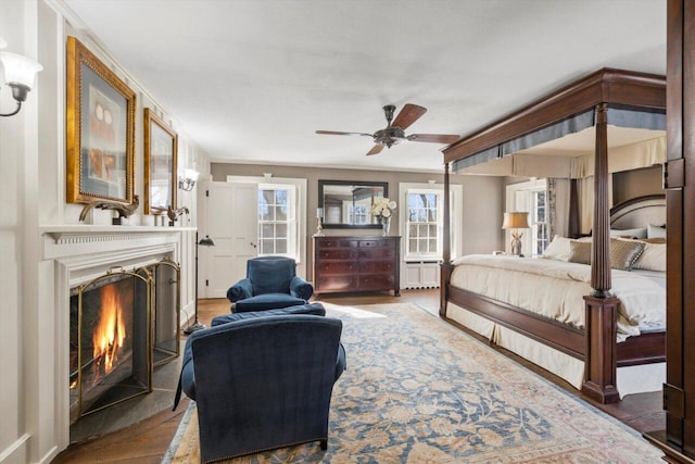 bedroom with a lit fireplace and wood finished floors