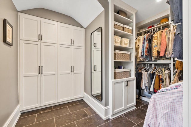 walk in closet with lofted ceiling and dark tile patterned flooring