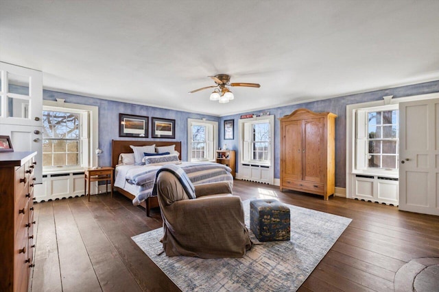 bedroom with a ceiling fan, multiple windows, and dark wood-type flooring