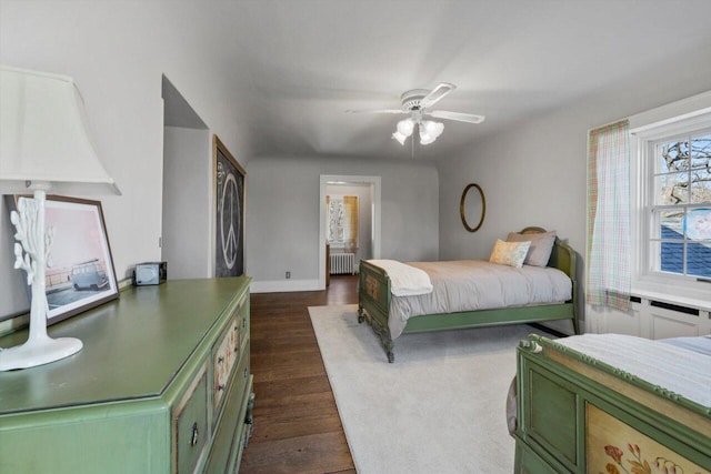 bedroom featuring baseboards, ceiling fan, dark wood-style floors, and radiator heating unit