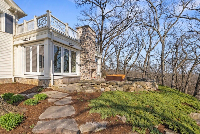view of property exterior with a chimney and a balcony