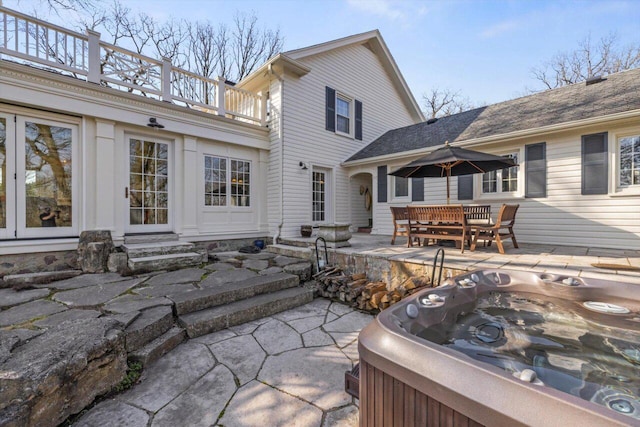 back of house featuring entry steps, a hot tub, a patio area, and a balcony
