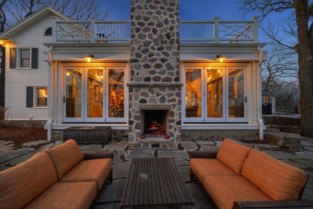 back of house with an outdoor living space with a fireplace, a chimney, a patio area, and a balcony