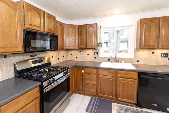 kitchen with brown cabinetry, decorative backsplash, dark countertops, a sink, and black appliances