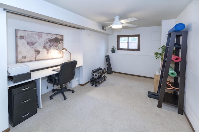 office space featuring a ceiling fan, baseboards, and light colored carpet
