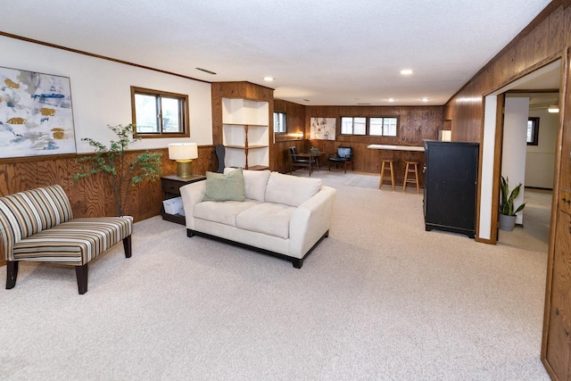 living area with recessed lighting, wood walls, light carpet, and ornamental molding