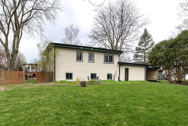 back of property featuring a lawn and fence