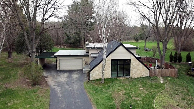 view of front of house with a garage, a front lawn, aphalt driveway, fence, and stone siding