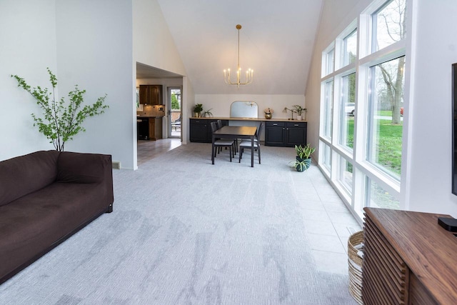 interior space with a healthy amount of sunlight, high vaulted ceiling, light colored carpet, and a chandelier