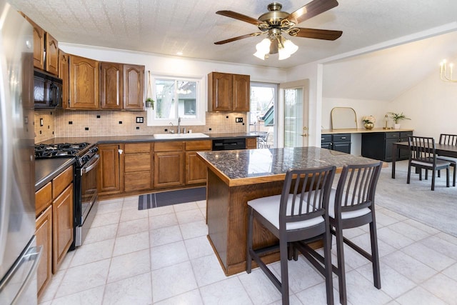 kitchen with brown cabinetry, black appliances, a breakfast bar, and tasteful backsplash