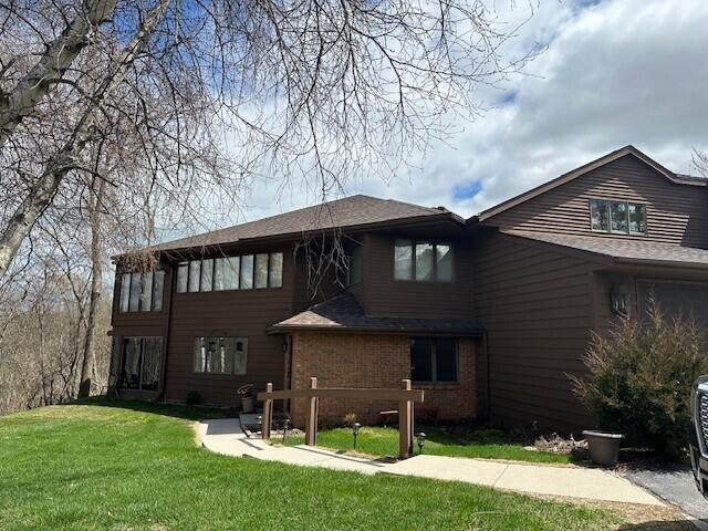 rear view of house with a lawn and brick siding