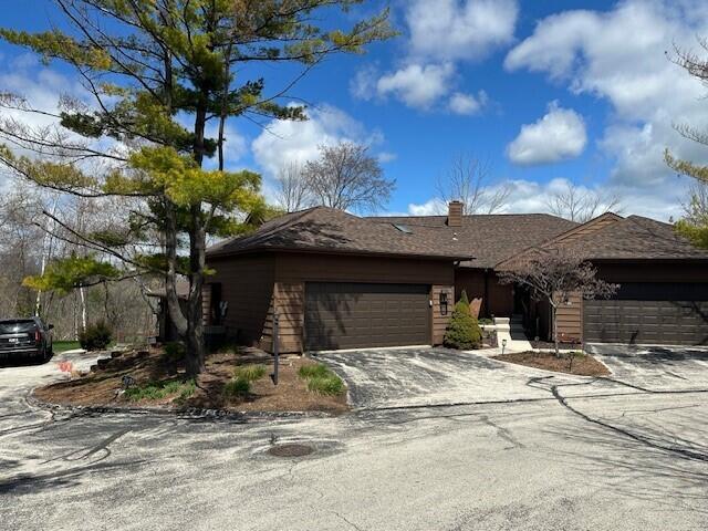 view of front of property featuring an attached garage, driveway, and a chimney