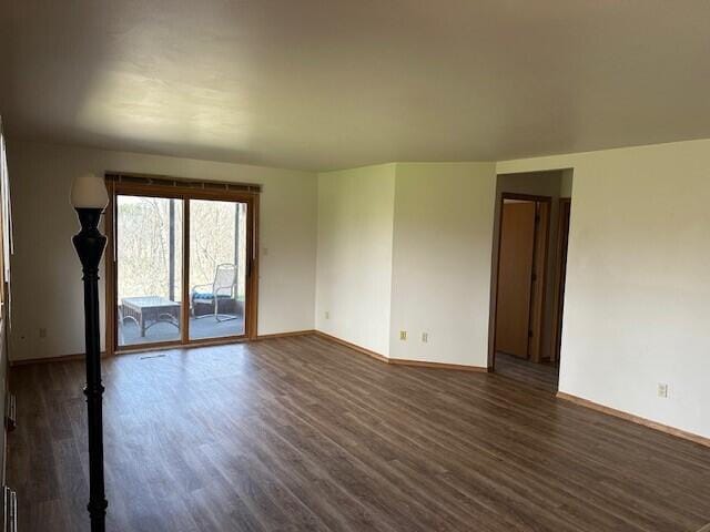 empty room featuring baseboards and dark wood-style floors