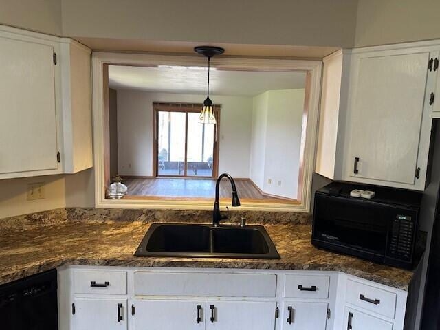 kitchen with a sink, white cabinets, black appliances, and pendant lighting