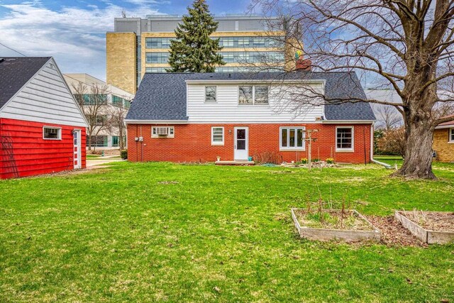 901 E Grant St, Appleton, WI 54911 - back of property with a lawn, brick siding, an AC wall unit, and a vegetable garden