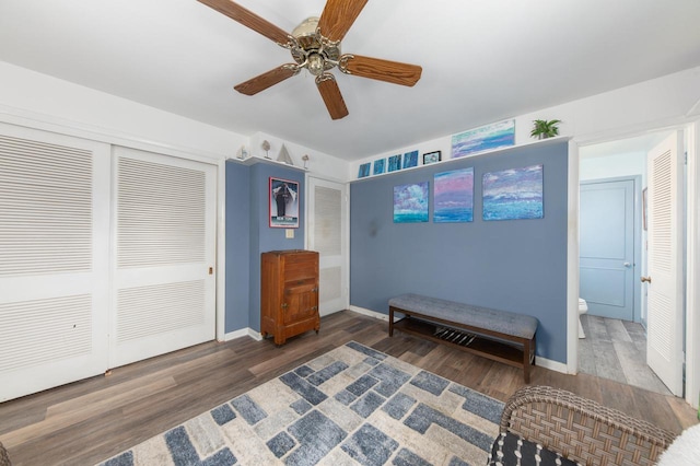 sitting room with a ceiling fan, baseboards, and wood finished floors