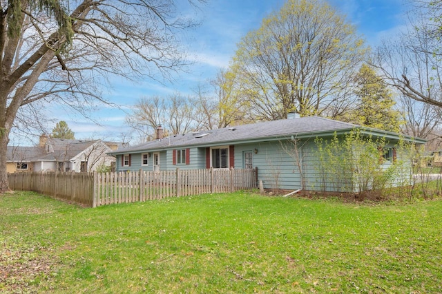 rear view of house featuring fence private yard, a yard, and a chimney