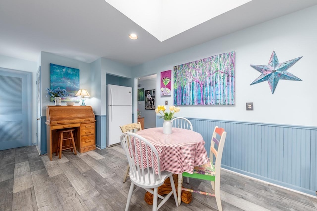 dining space with light wood-type flooring, recessed lighting, and a skylight
