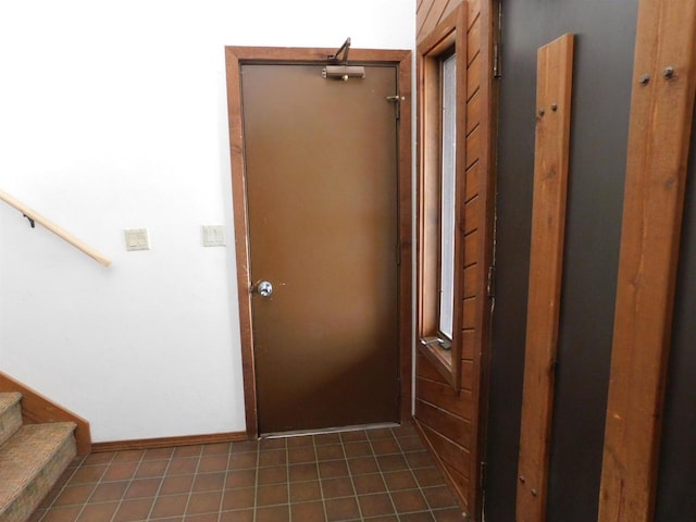 entryway featuring baseboards, tile patterned flooring, and stairs