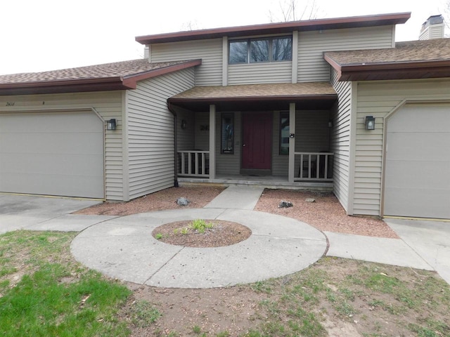 view of front facade with a shingled roof, covered porch, an attached garage, and concrete driveway