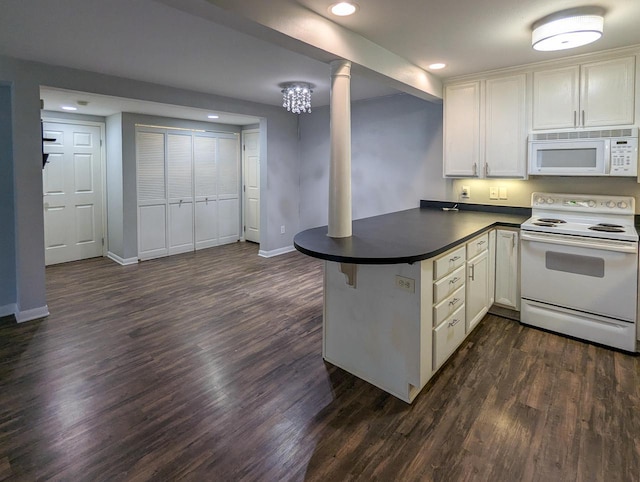 kitchen featuring a peninsula, dark countertops, white appliances, recessed lighting, and dark wood finished floors