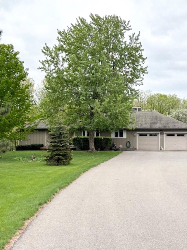 5021 Margaret Dr, Amherst, WI 54406 - obstructed view of property featuring driveway, a front yard, a garage, and roof with shingles