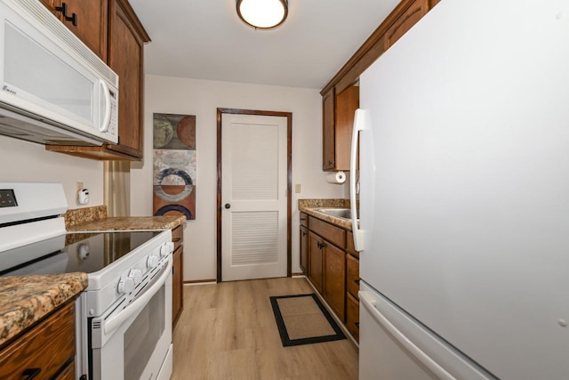 kitchen with light wood-style floors, brown cabinets, and white appliances