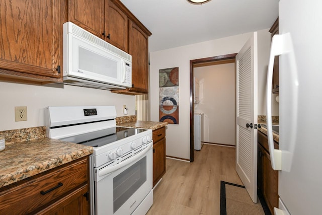 kitchen featuring light wood-style flooring, brown cabinets, and white appliances