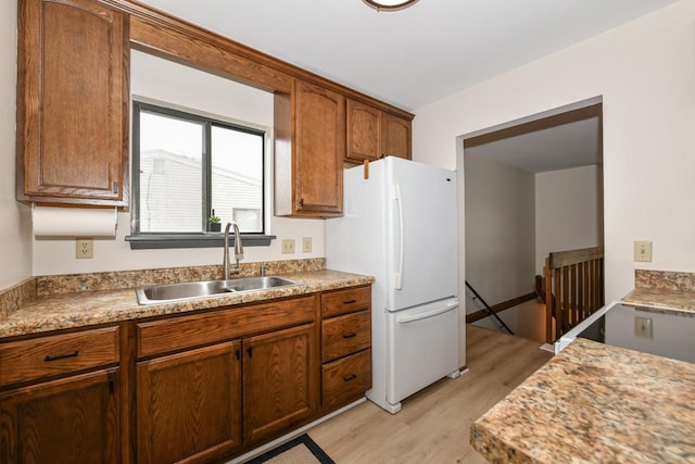 kitchen with a sink, light countertops, freestanding refrigerator, and light wood-style flooring