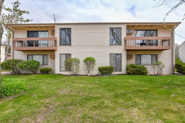 rear view of house with a lawn and a balcony